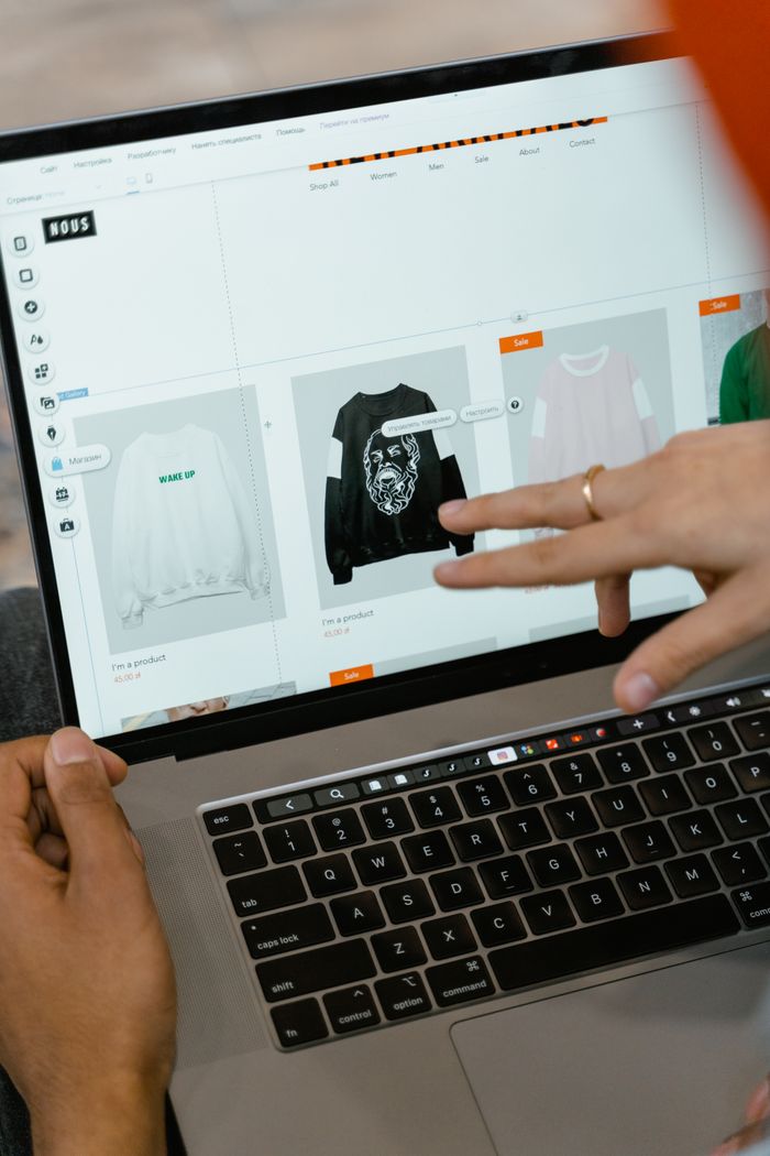 Gros plan sur des mains interagissant avec un site de shopping sur l’écran d’un ordinateur portable à l’intérieur.